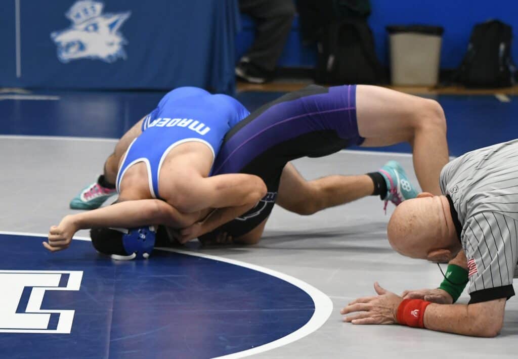 Coyote wrestler pins opponent during match at Madera tournament.