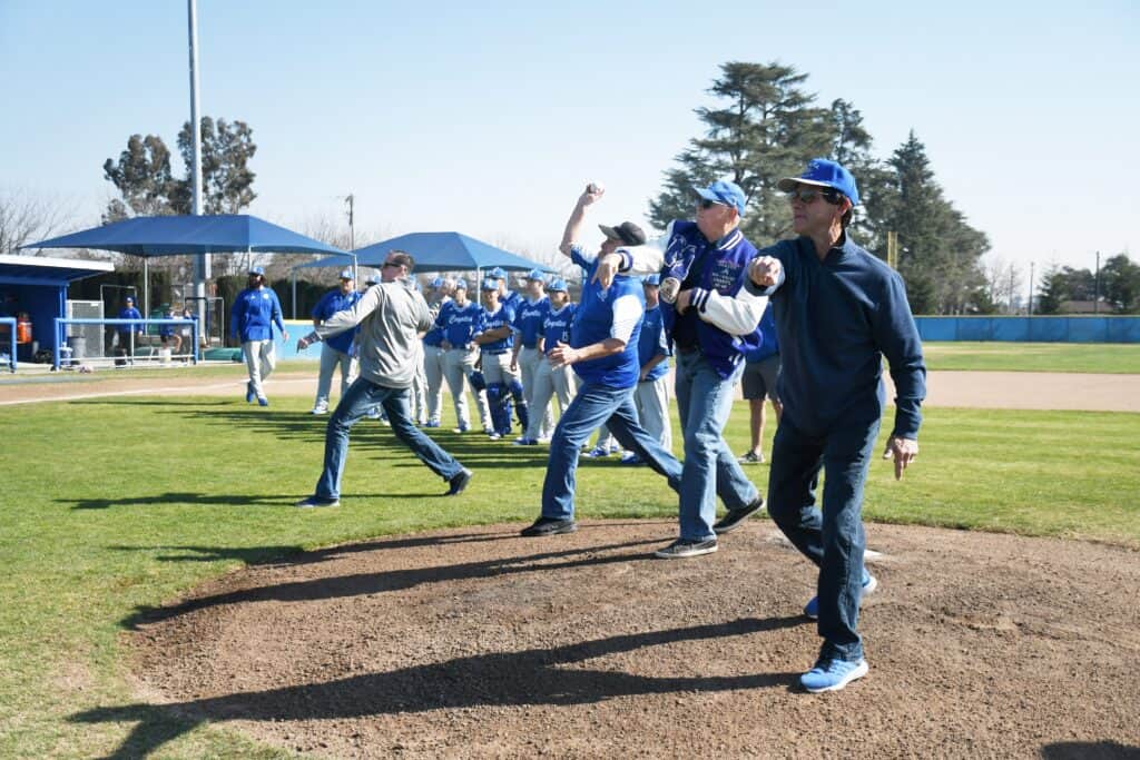 Coyotes players and coaches celebrating on the baseball field after a victory.