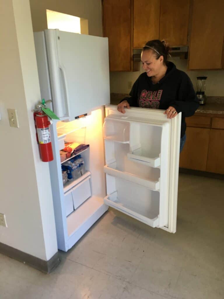 Woman opening empty refrigerator in cozy kitchen, preparing for winter.