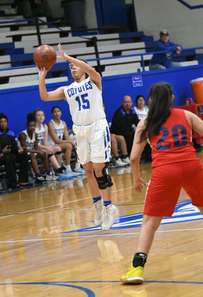 Coyotes player shooting basketball during game against Apaches.