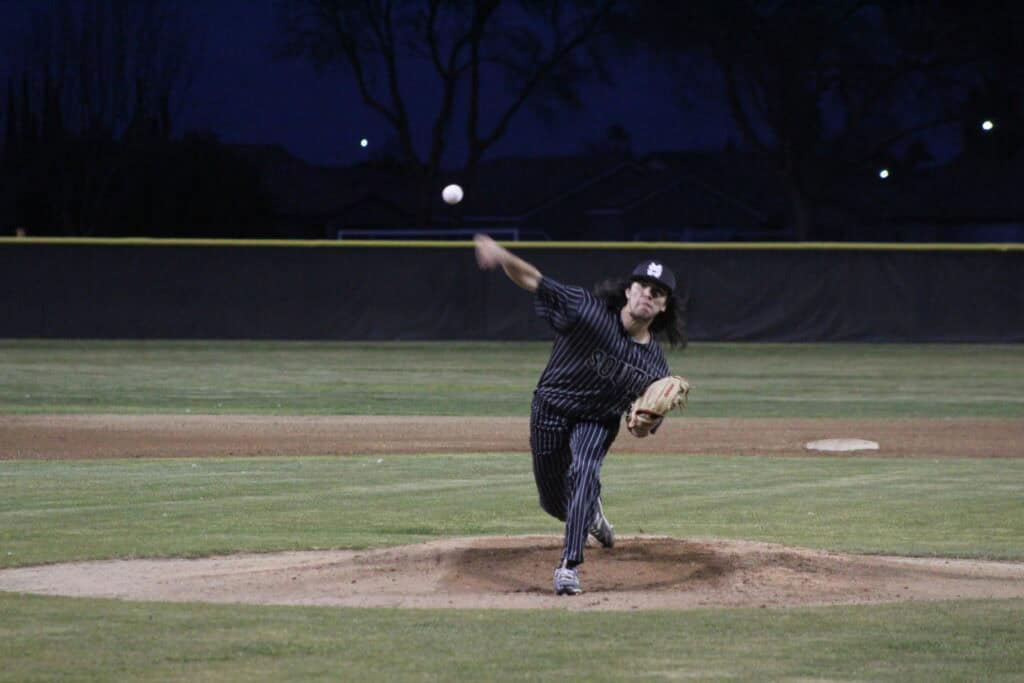 Madera Stallions pitcher throws during a game at night.