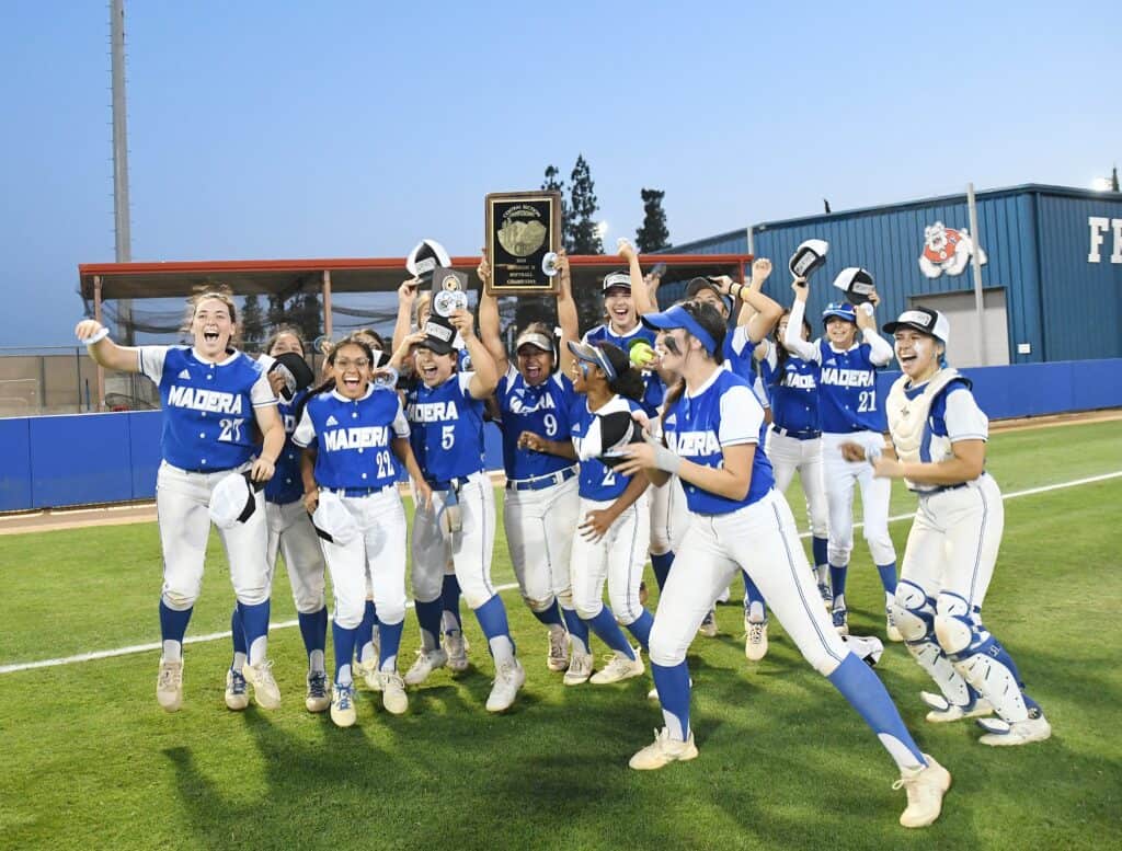 Coyotes softball team celebrating with trophy after winning championship.