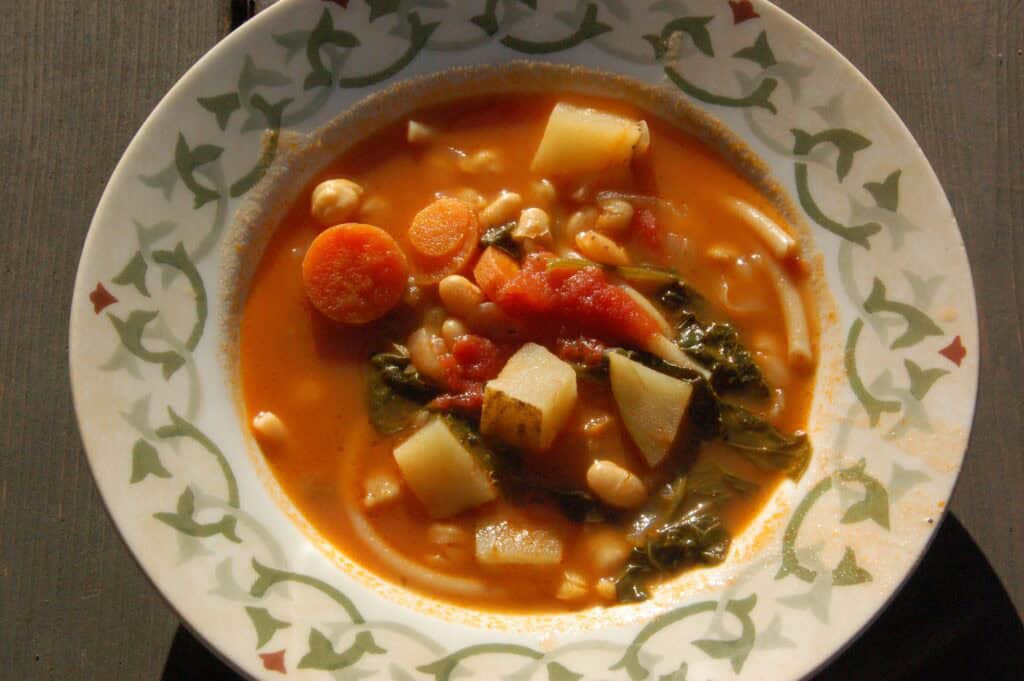 Warm vegetable soup with carrots, potatoes, and greens in a bowl.