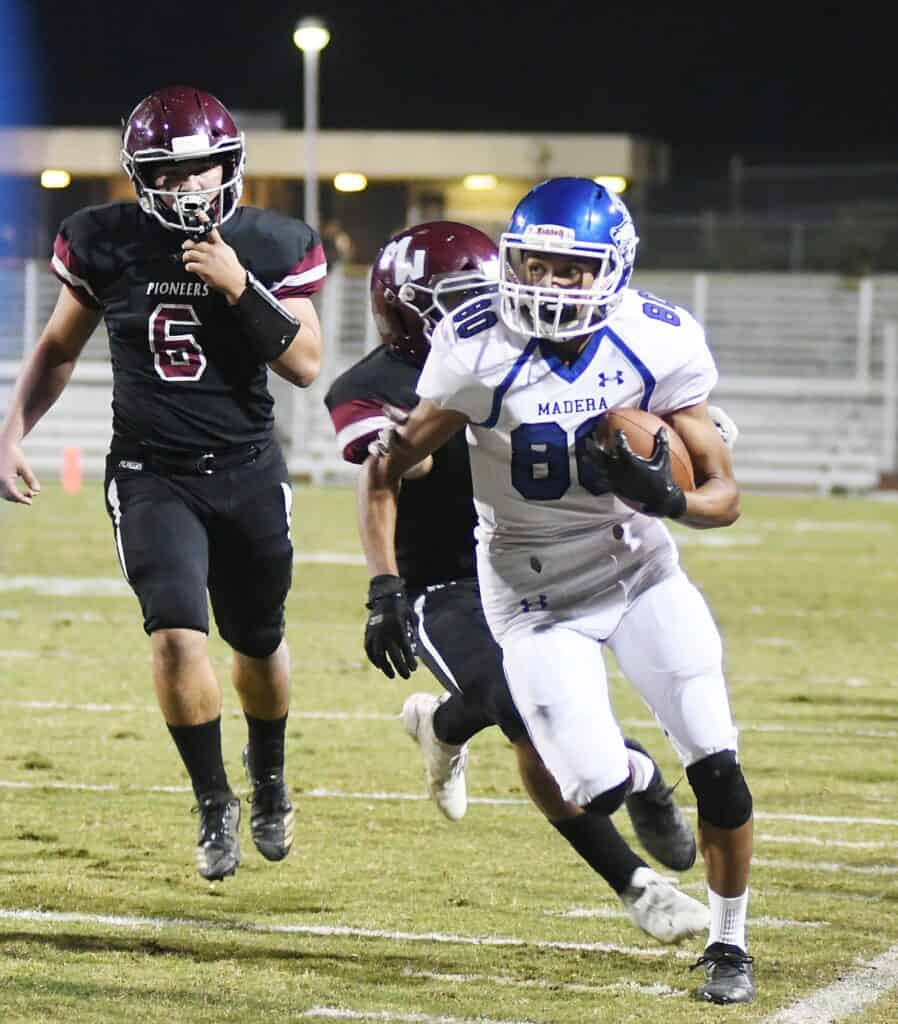 Madera football player in white jersey with ball, pursuing victory.