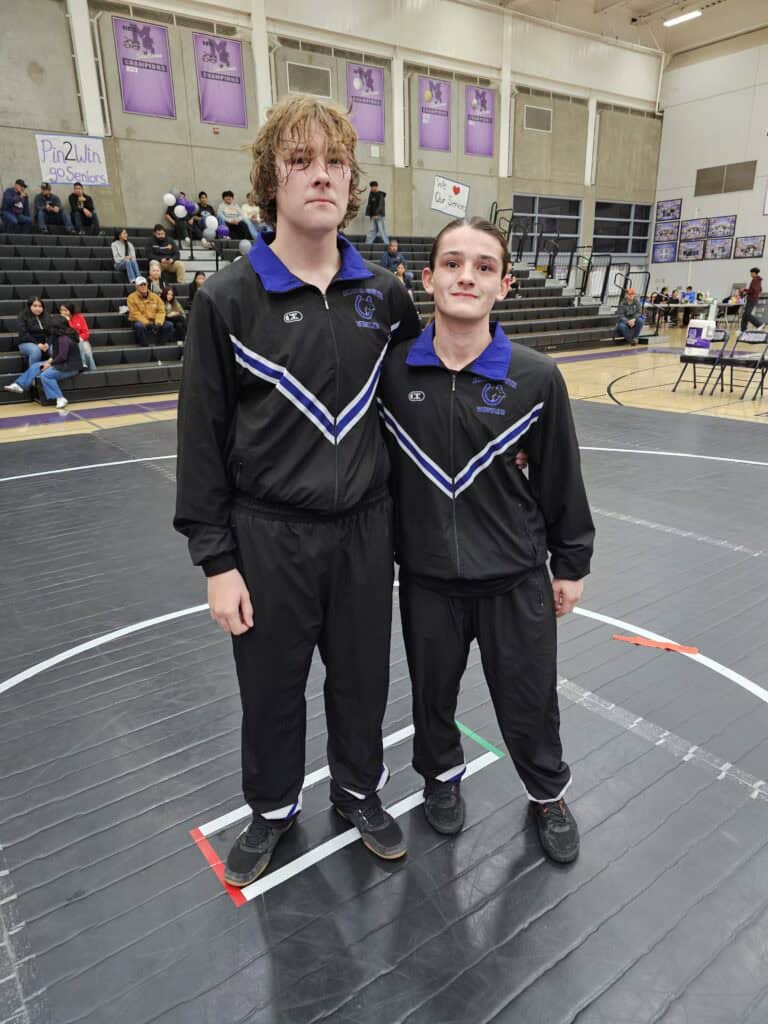 Two young athletes in Madera Stallions jackets at a basketball game honoring seniors.
