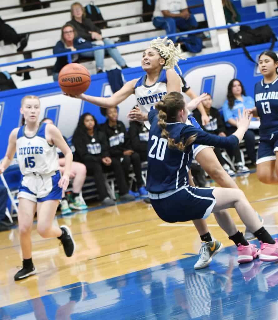 Youth girls basketball game with players competing fiercely on the court.