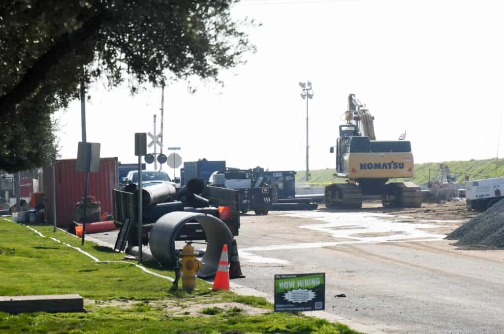 Sewer repair construction site with heavy machinery and workers in progress.