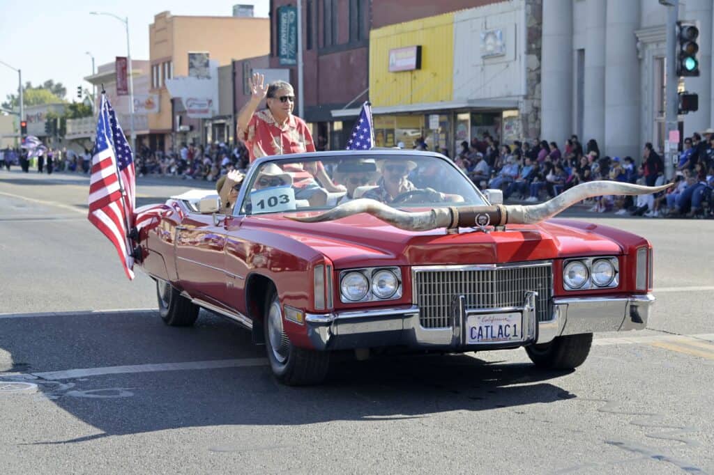 Vintage red convertible with flags during Old Timers’ Day parade in Madera.
