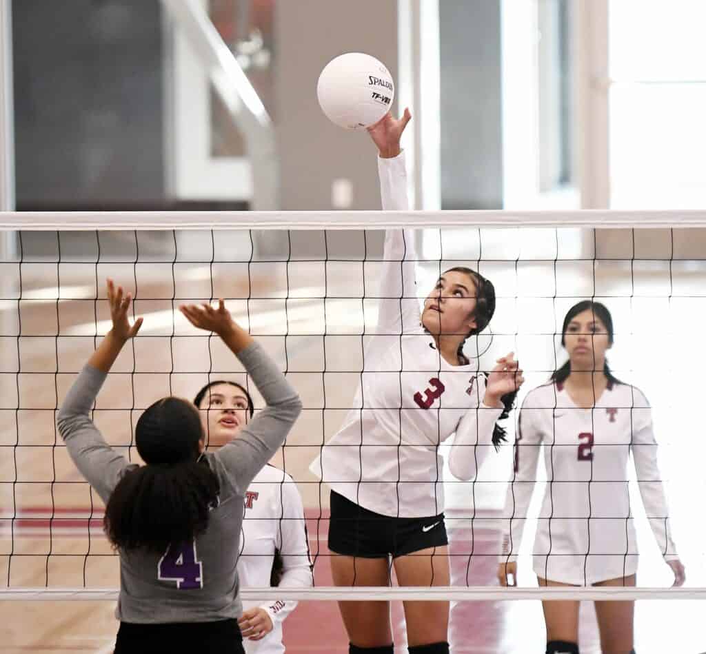 Volleyball players competing at Madera High School gym.