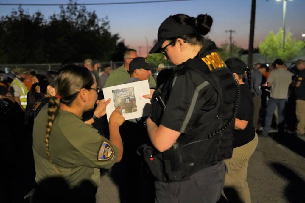 Police officers and volunteers discuss search efforts for missing child.