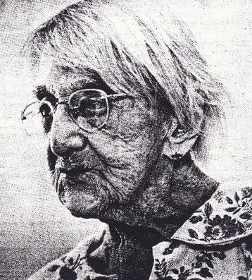Black and white photo of Maude, an elderly woman with glasses and short hair.
