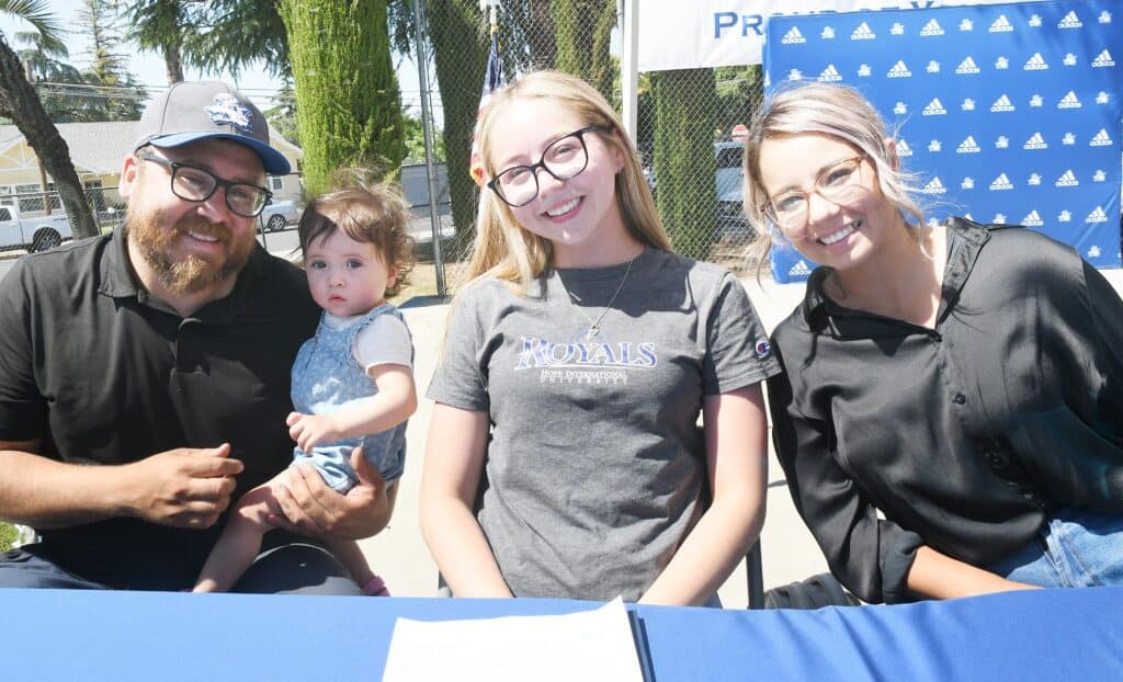 Hernandez signs as second stunt cheerleader at Madera event with family and coaches.