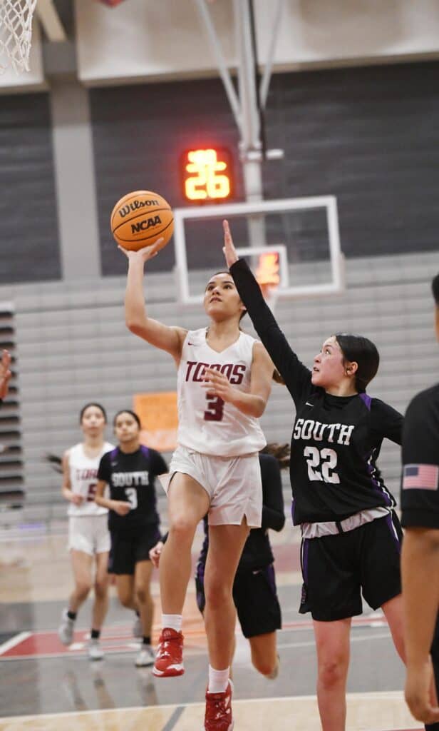 Female basketball player shooting during a game at Madera gym.