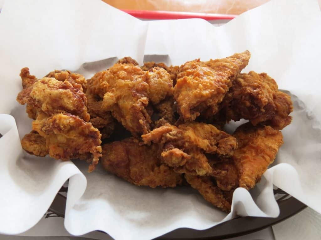 Fried chicken pieces on white paper, symbolizing classic American comfort food.