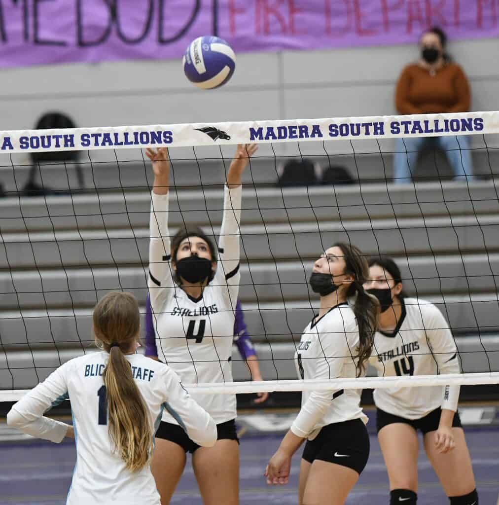 Madera South Stallions volleyball players blocking at the net during a game.