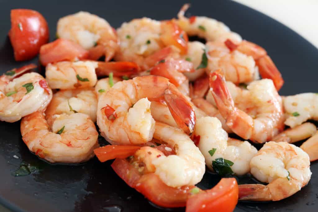 Delicious shrimp prepared in multiple styles served on a black plate. Perfect for seafood lovers and.