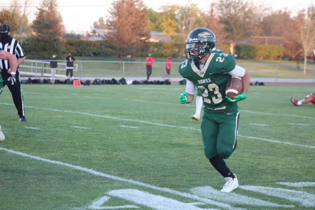 Madera Hawks running back with ball during game.