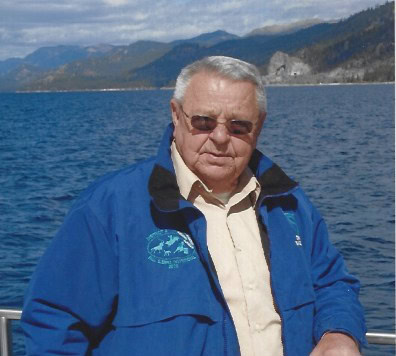 Portrait of Duane A. Smartt by a lake with mountains in background.