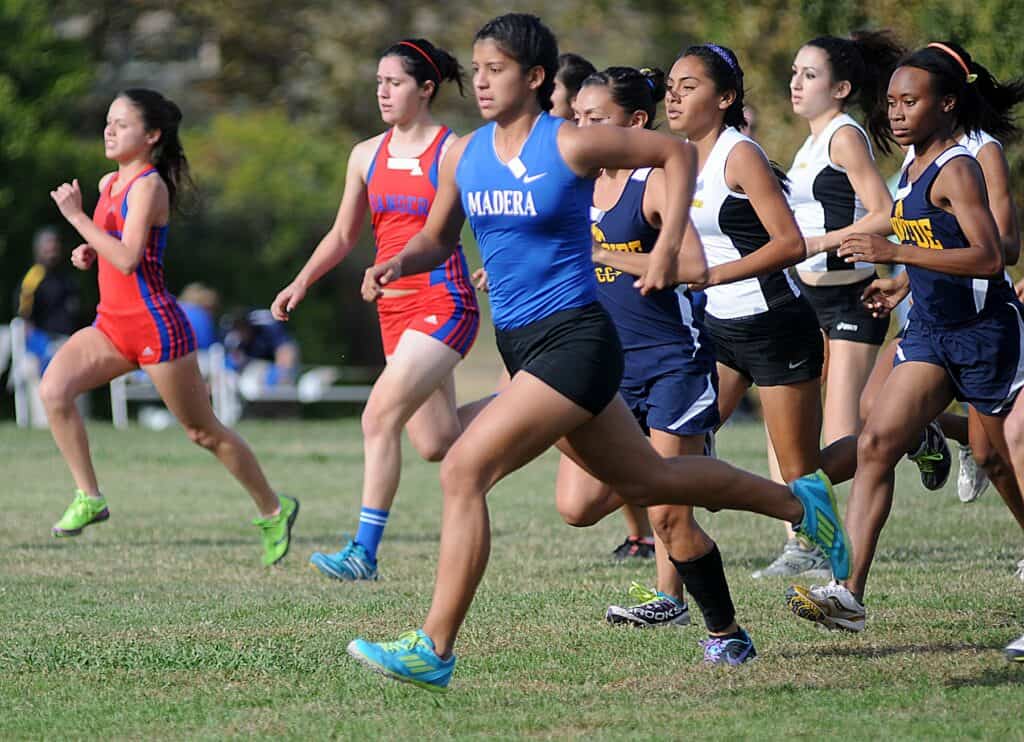 Madera Hawks girls cross country runners competing in a race outdoors.