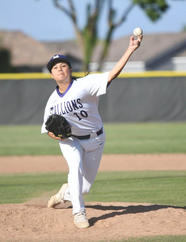 Young female baseball pitcher in action on the mound.