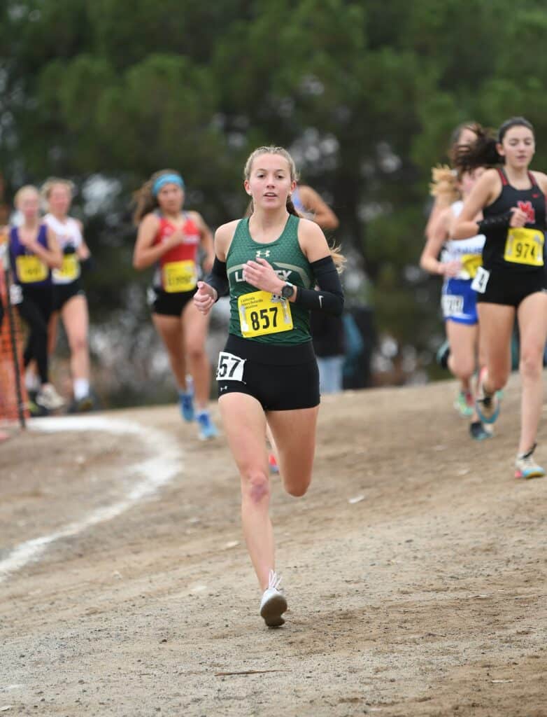 Young female runner competing in cross country race at state meet event.
