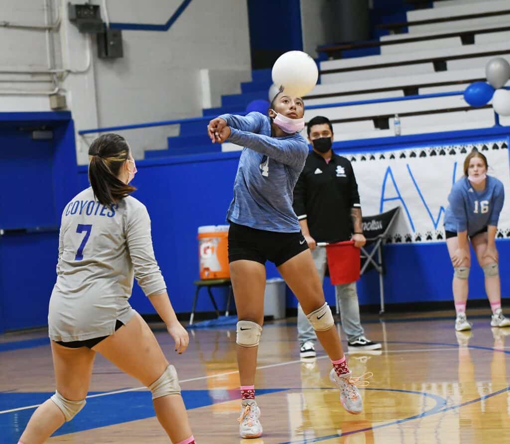 Madera volleyball player spiking the ball during a match in the gym.