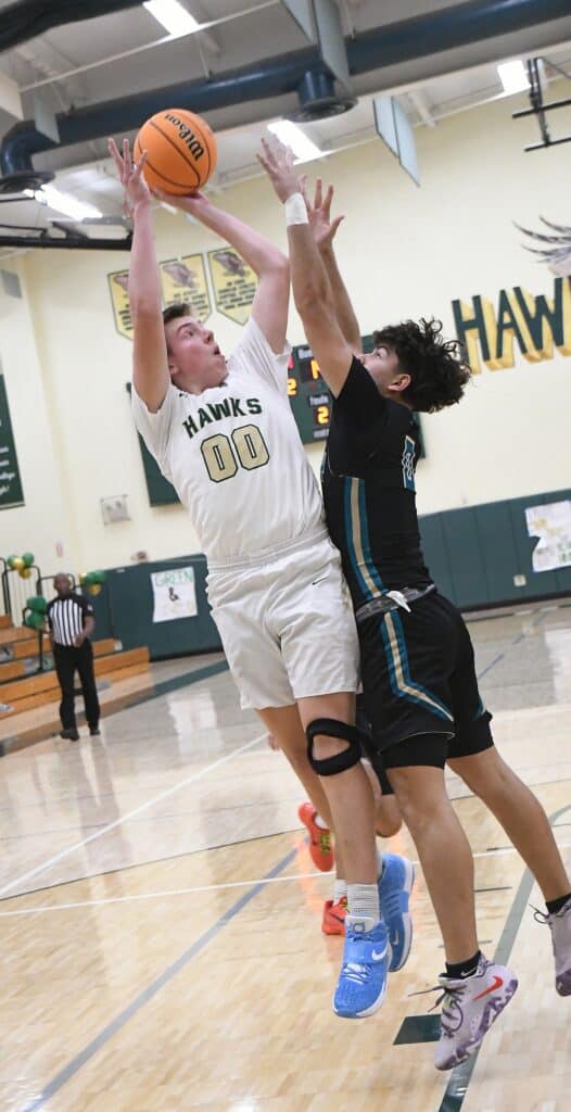 Madera Hawks player shooting basketball over defender in gym.