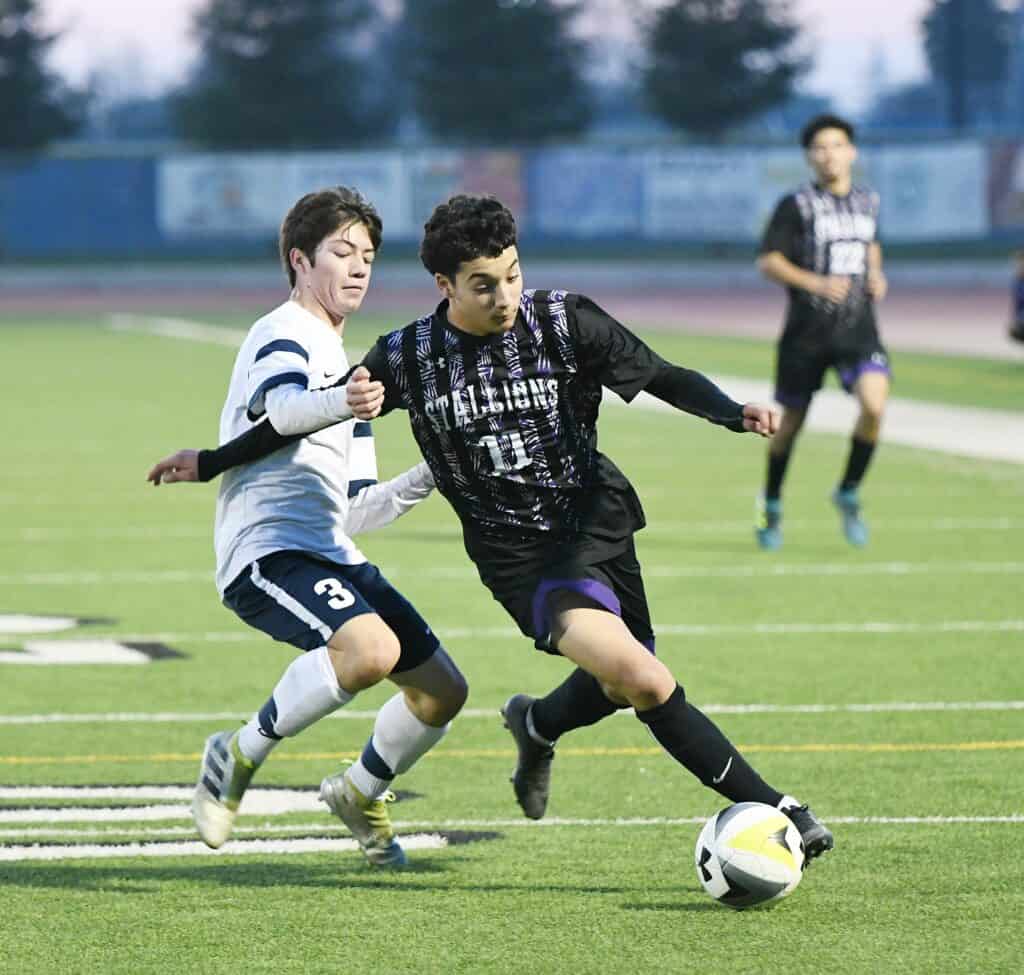 Young soccer players competing in a high school game.