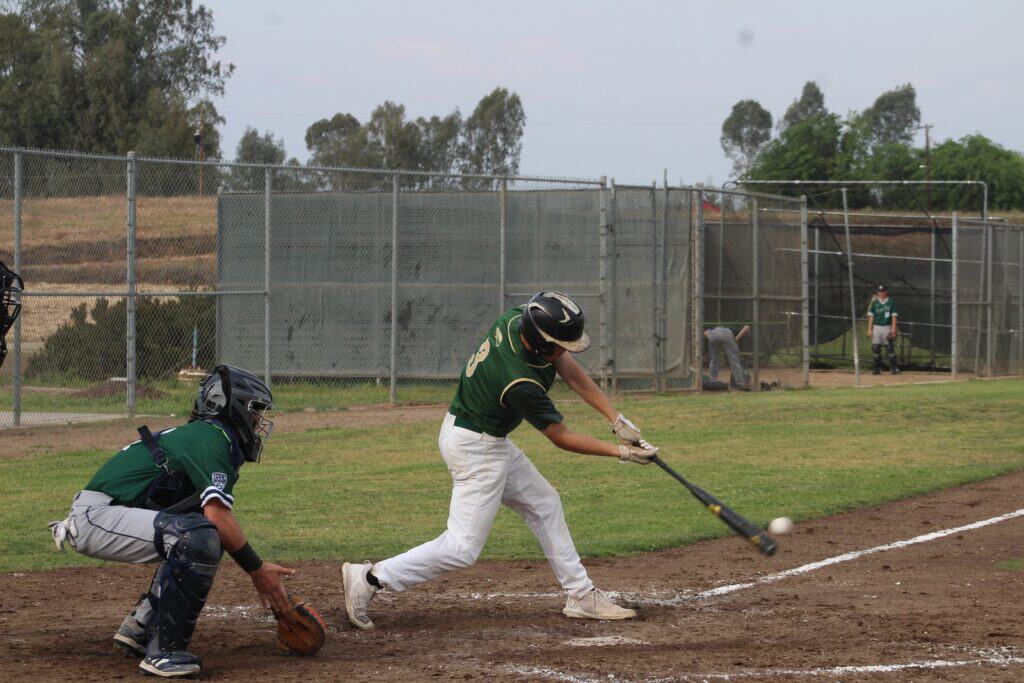 Player swinging bat during baseball game at Madera field.