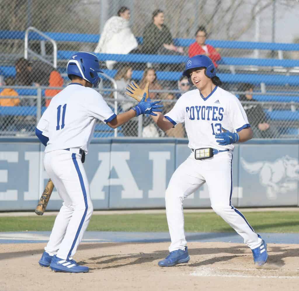 Coyotes players celebrating after scoring in a baseball game.