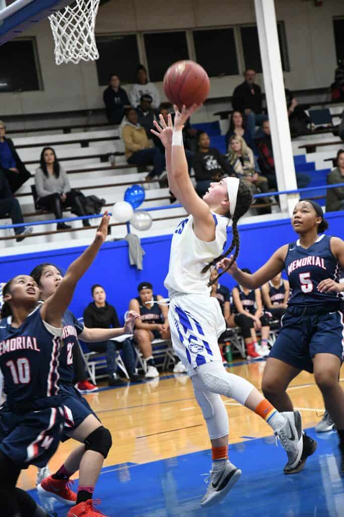 Young female basketball player attempting a shot during a game.