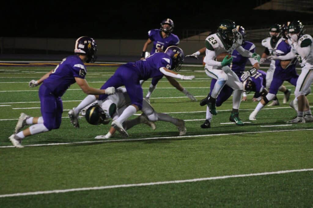 Madera Hawks football players in action during a night game on the field.