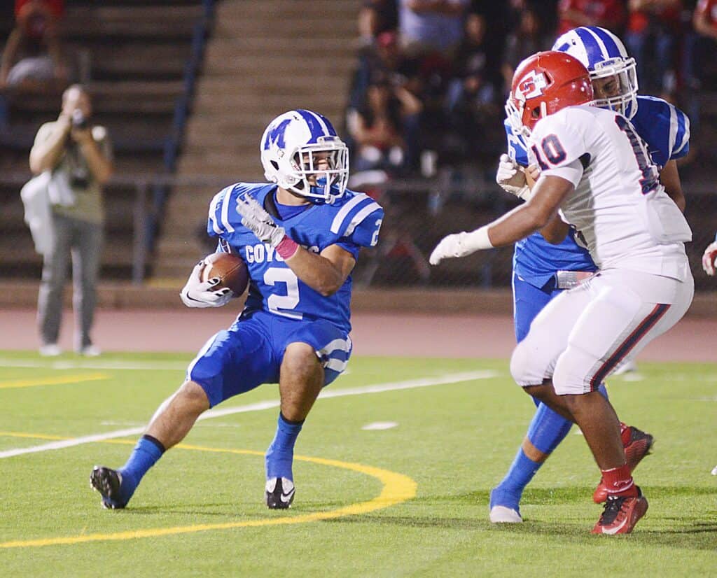 Former Coyote football player running with ball against opponents in Nebraska game.