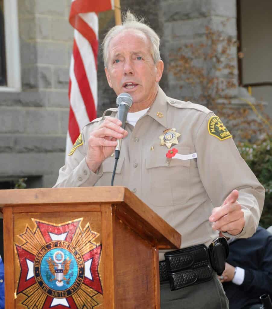 Sheriff John Anderson speaking at a memorial event, honoring his service and dedication to the commu.