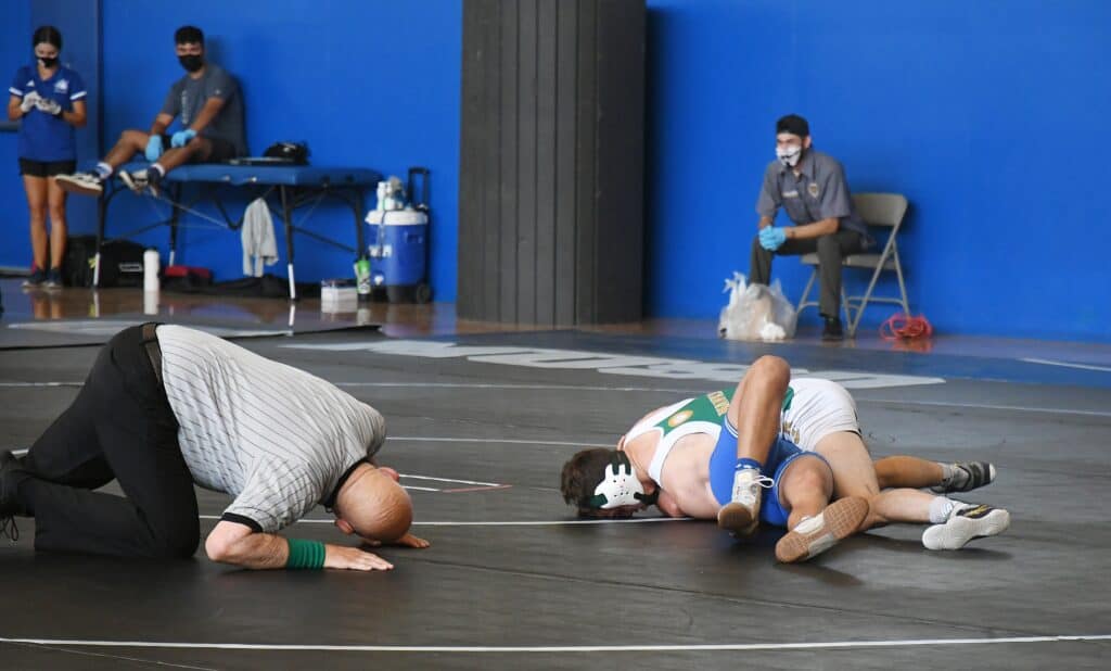 Two wrestlers competing in a match at Madera high school gym.