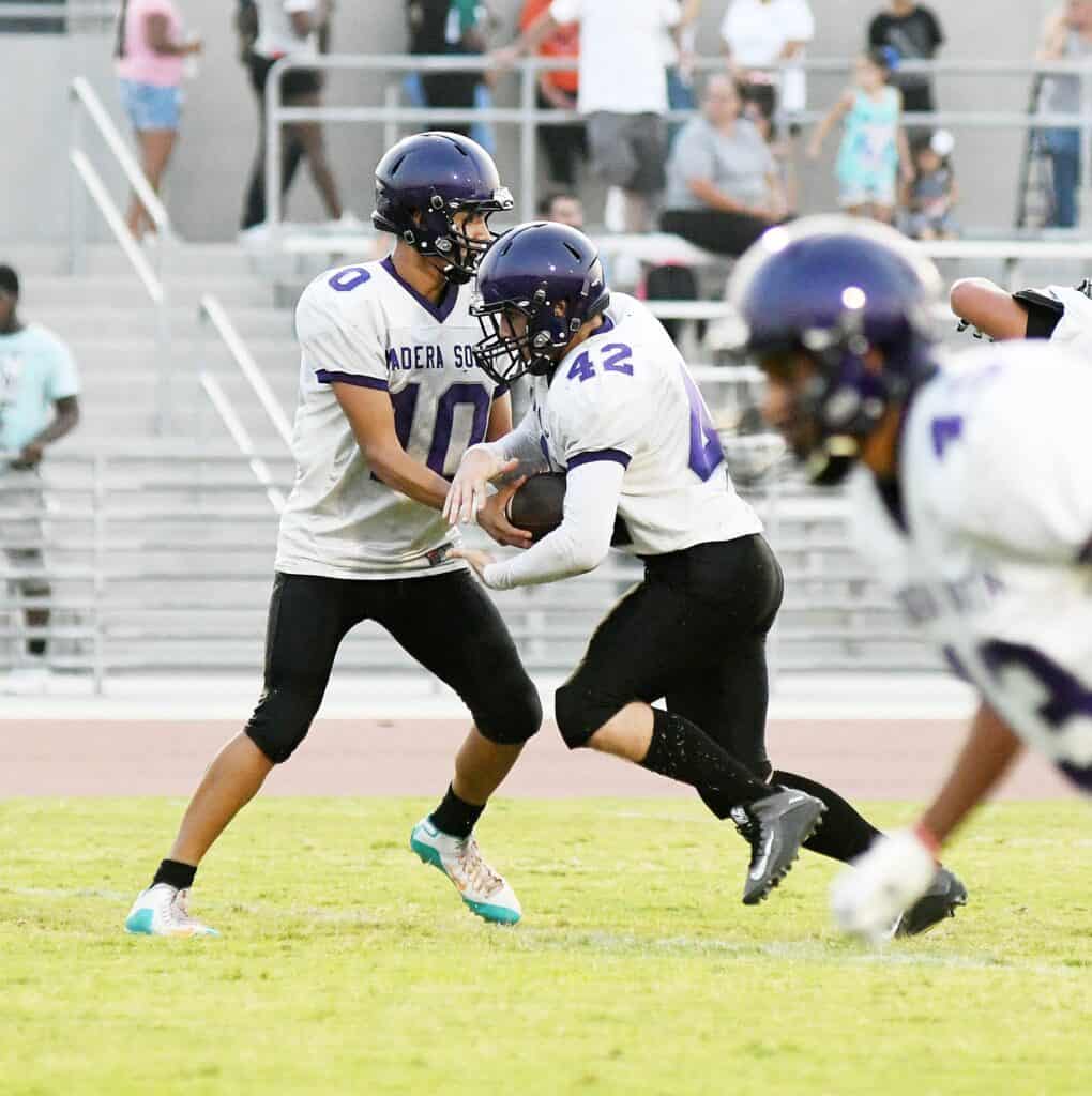 Madera South football players during game, focusing on teamwork and sportsmanship.