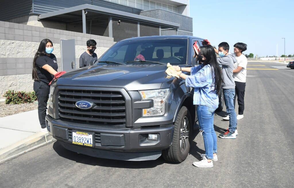 Community car wash event with kids cleaning a truck outdoors.