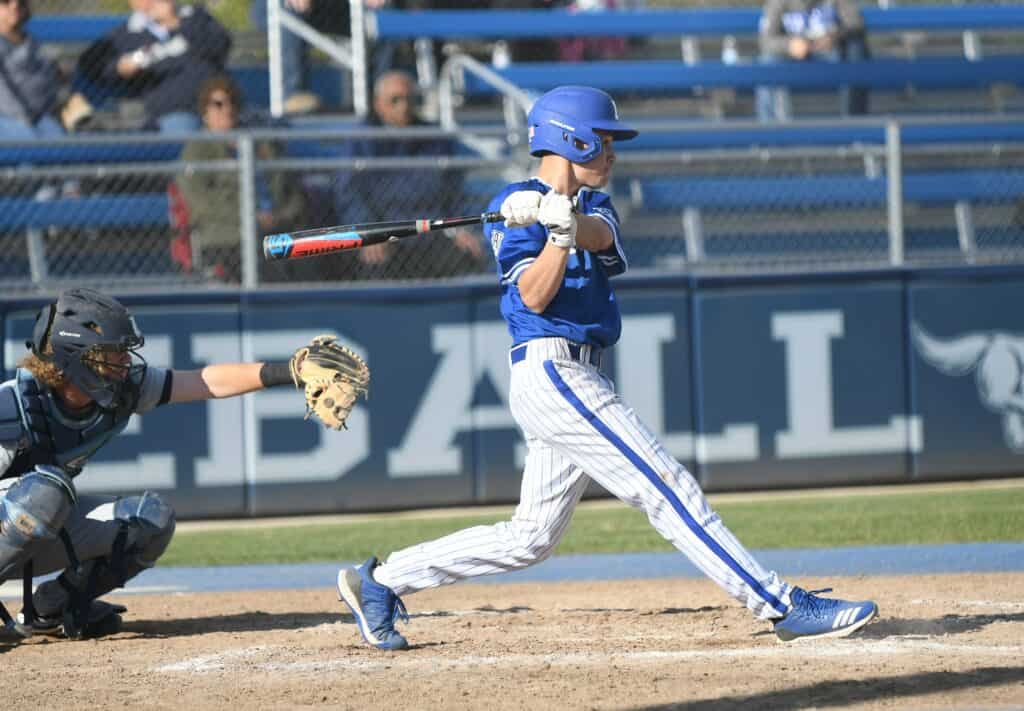 Young baseball player swinging at pitch during a game at Madera field.