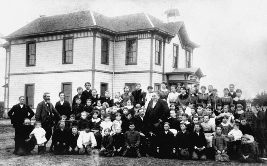 Historic black-and-white photo of students and teachers outside Madera school after explosion.