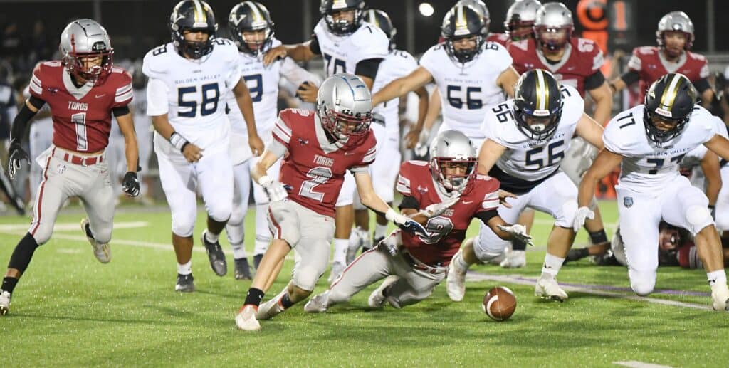Madera football players struggle during a game, highlighting team effort and challenges.