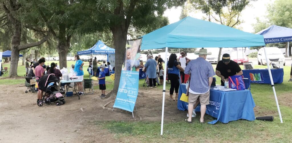 Community Resource Fair with booths and attendees outdoors.
