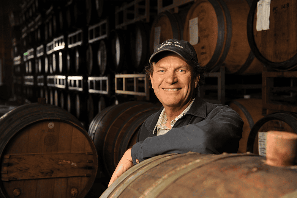 Wine pioneer receiving award in winery cellar.
