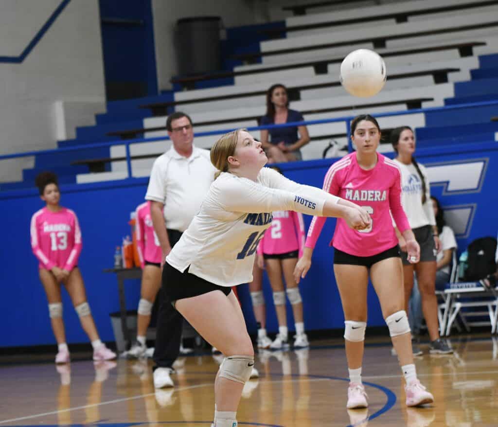 Volleyball player serving during a match at Madera gymnasium.