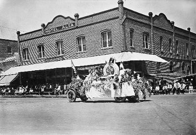 Vintage parade float in Madera honoring Dr. Howard L. James, with Hotel Alta in background.