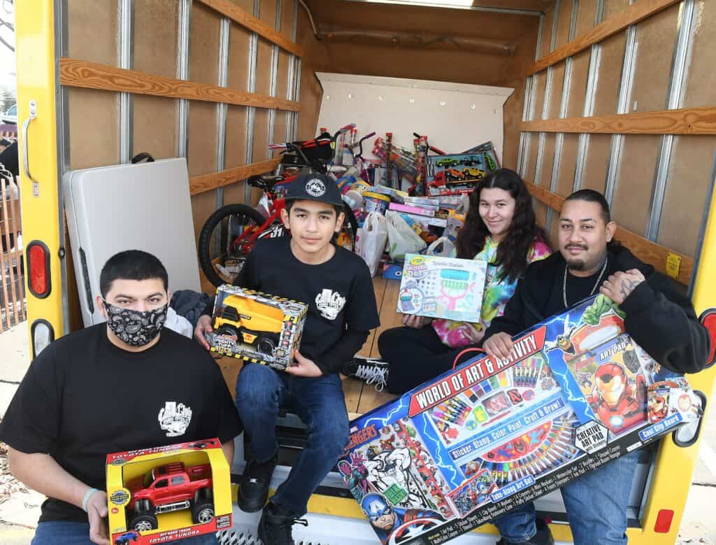 Car club volunteers with donated toys for charity in a truck.