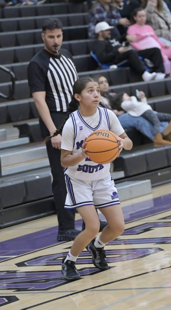 Young female basketball player prepares to shoot during game.