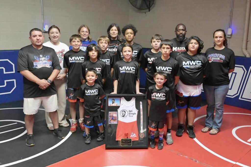 Madera Wrestling Club team with young athletes and coaches at an indoor gym.