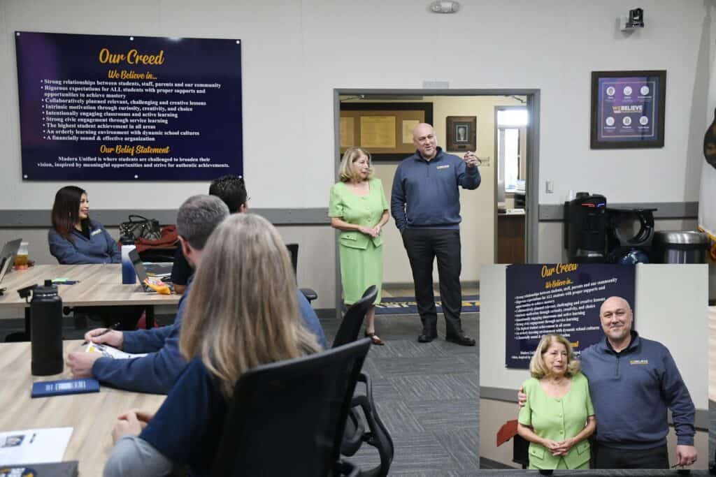 Community meeting with speakers and audience in a conference room.