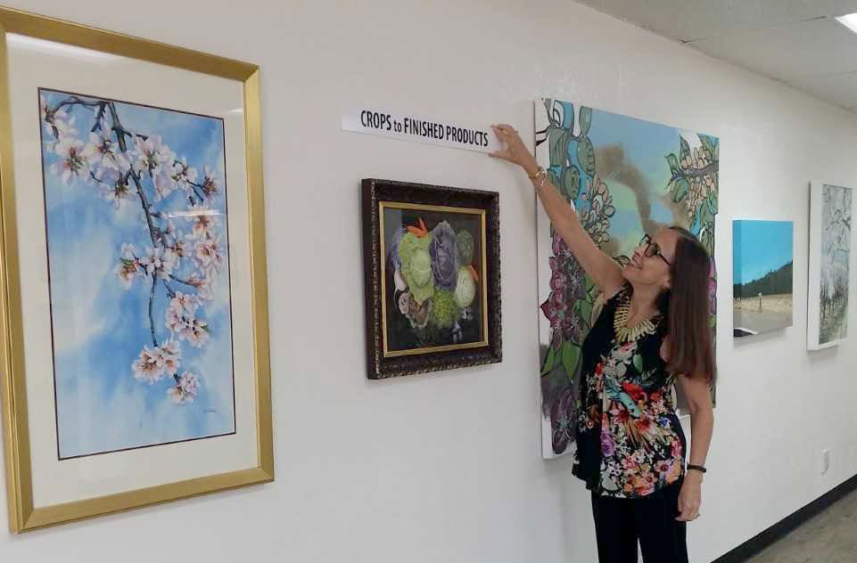 Woman pointing at artwork related to agriculture at a local event.