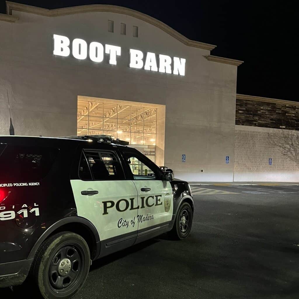 Police vehicle outside Boot Barn during night hours.